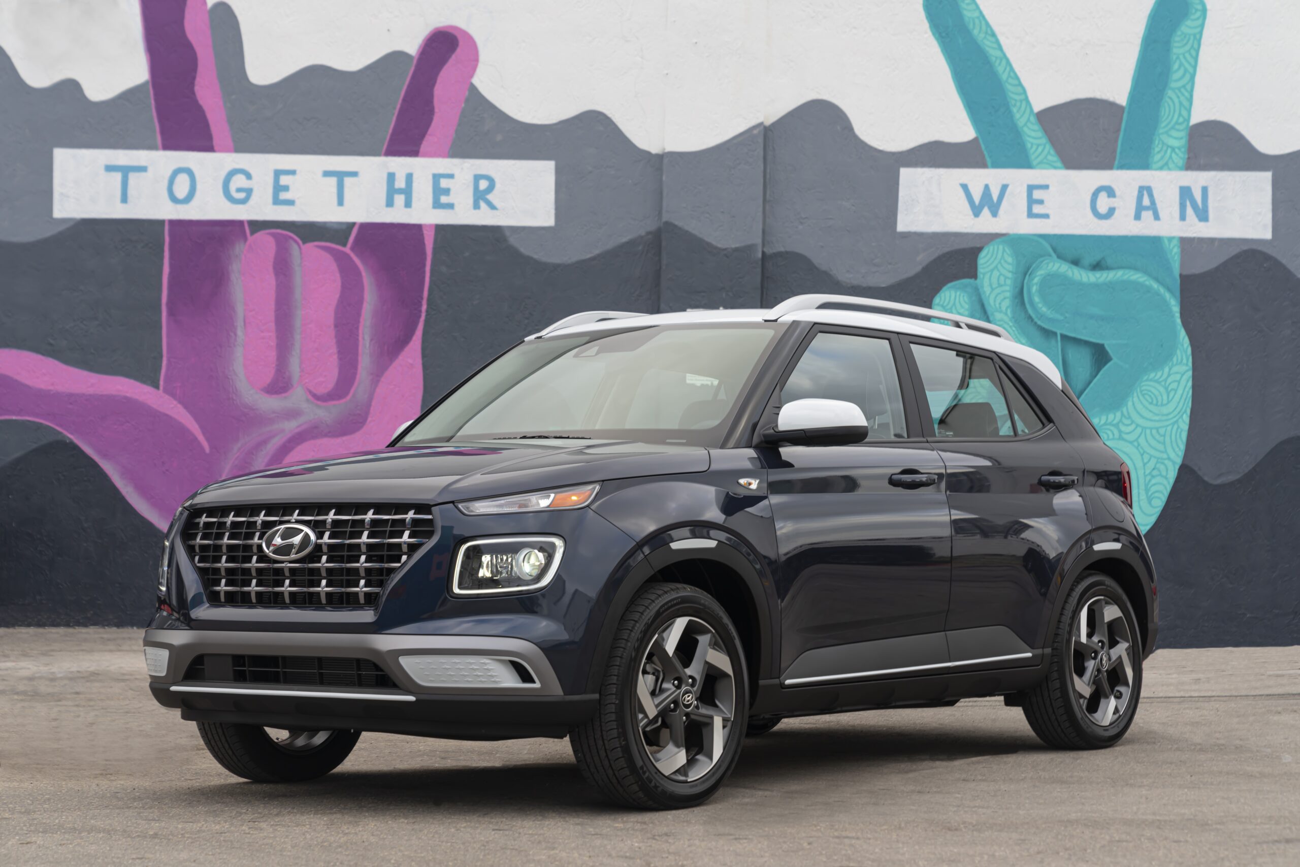 A sleek black SUV parked in front of a colorful mural.