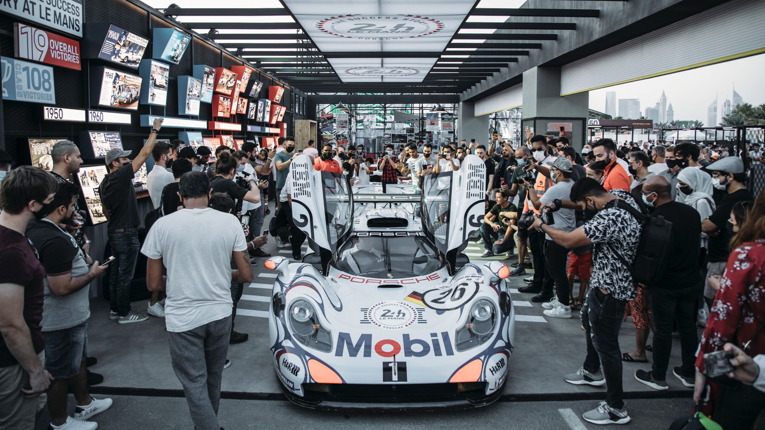 A race car on display surrounded by a crowd and photographers.