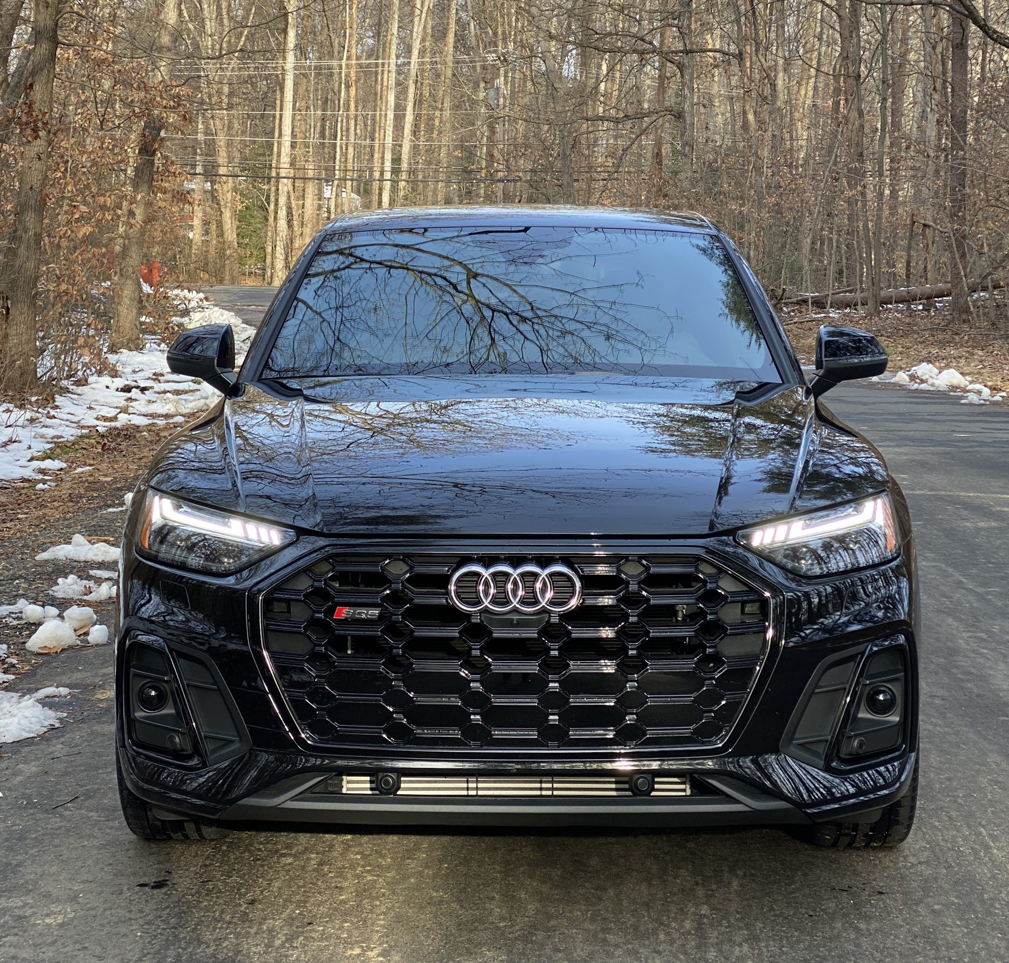 Front view of a black Audi SUV on a forest road.