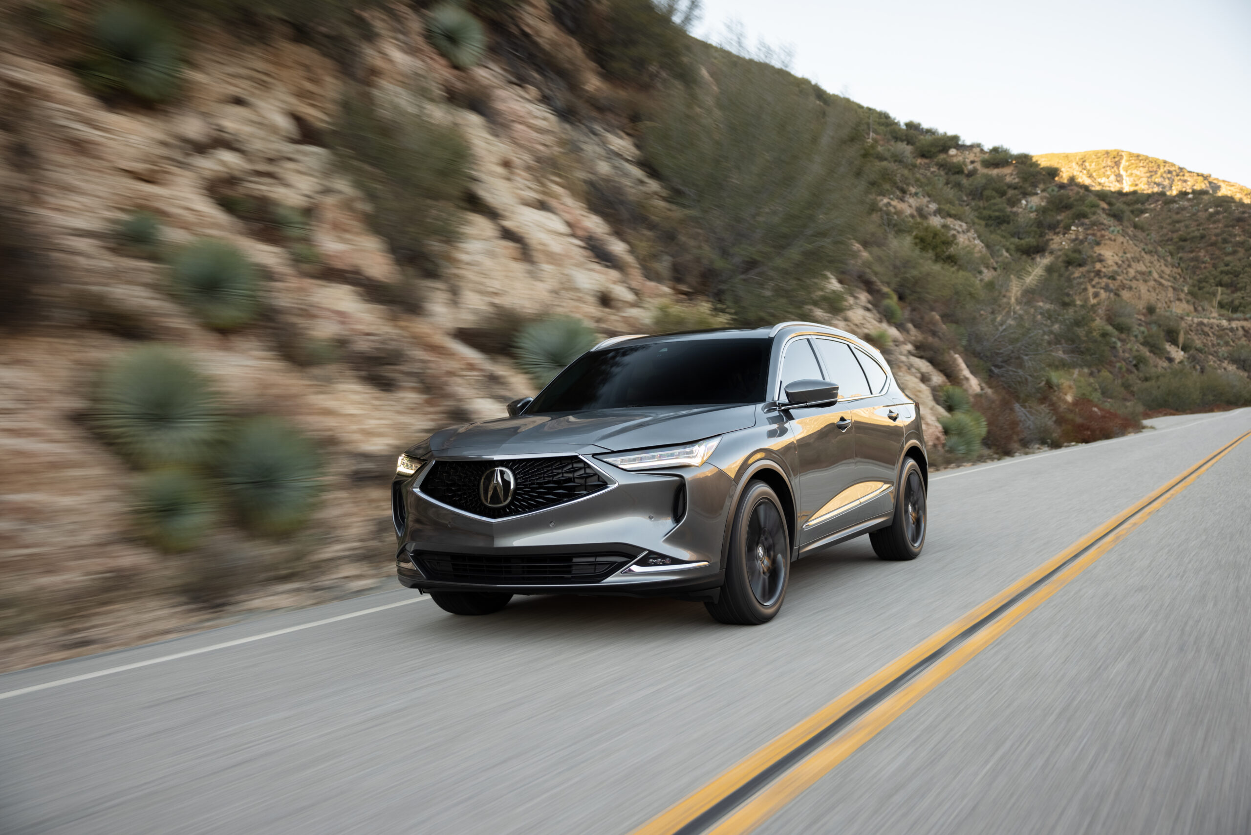 A sleek black SUV driving on a winding mountain road.