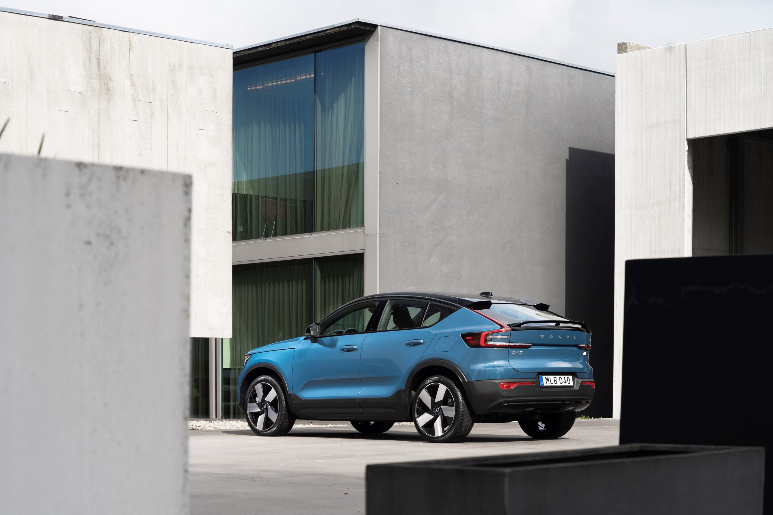 A sleek blue electric SUV parked outside a modern concrete building.
