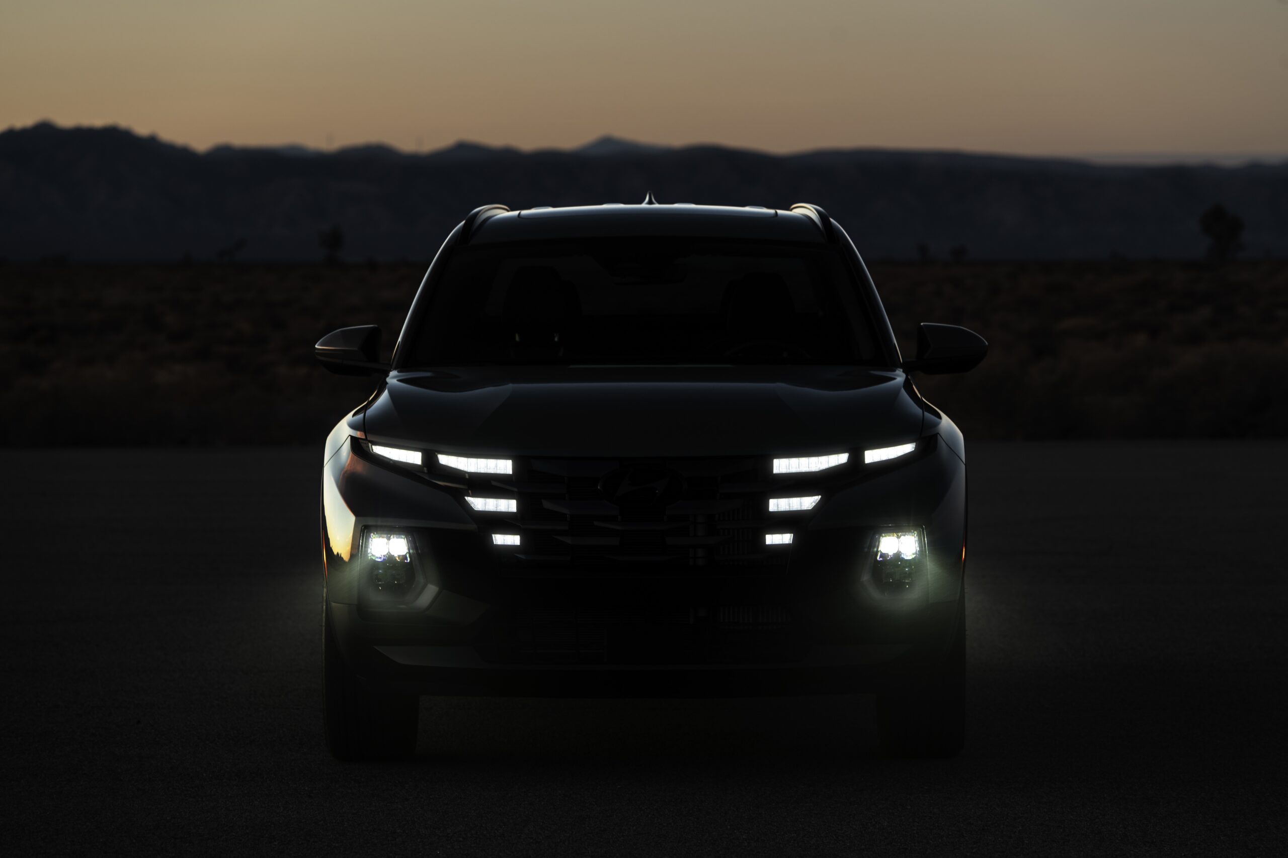 Front view of a modern SUV with distinct LED headlights at dusk.