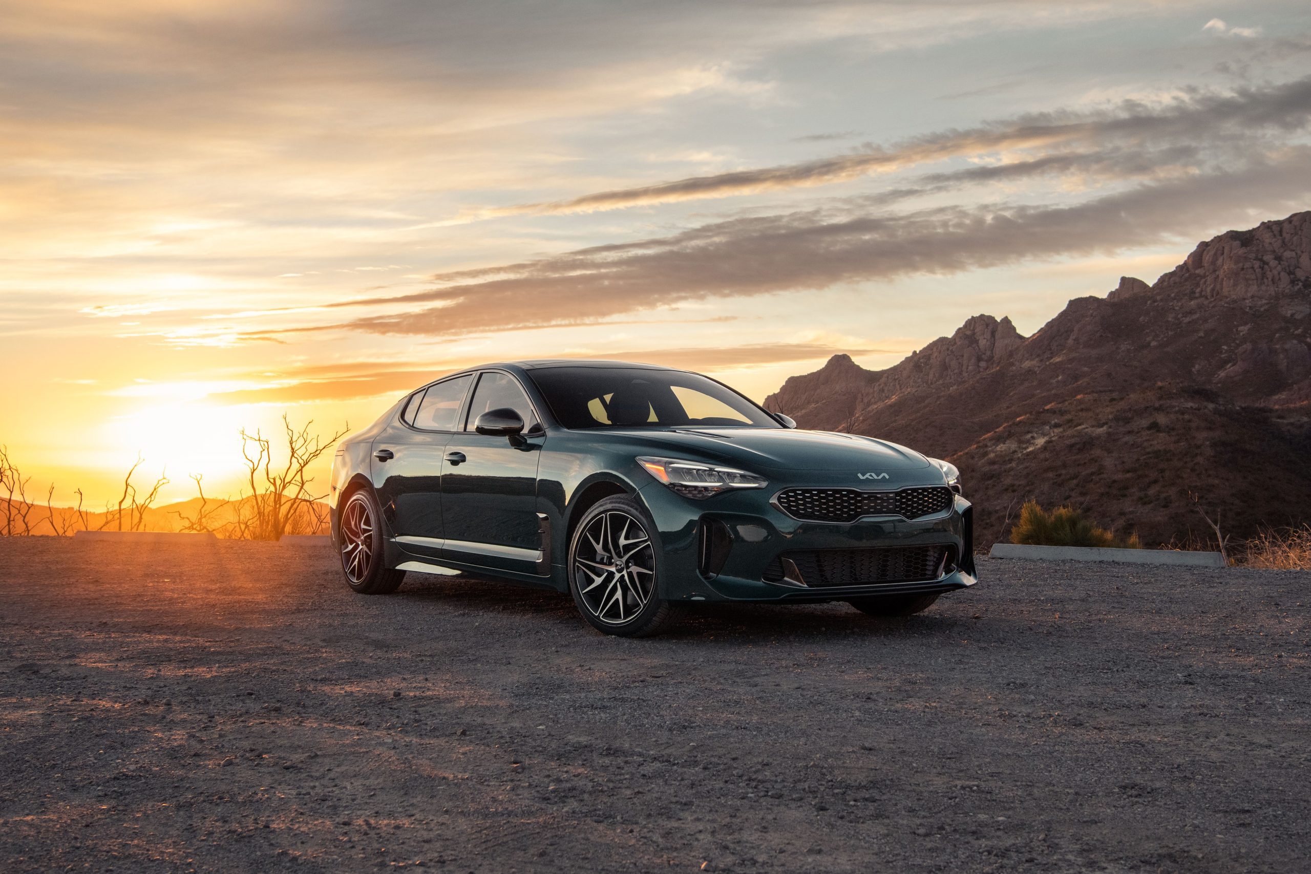 Sleek black sedan parked at sunset with mountains in the background.