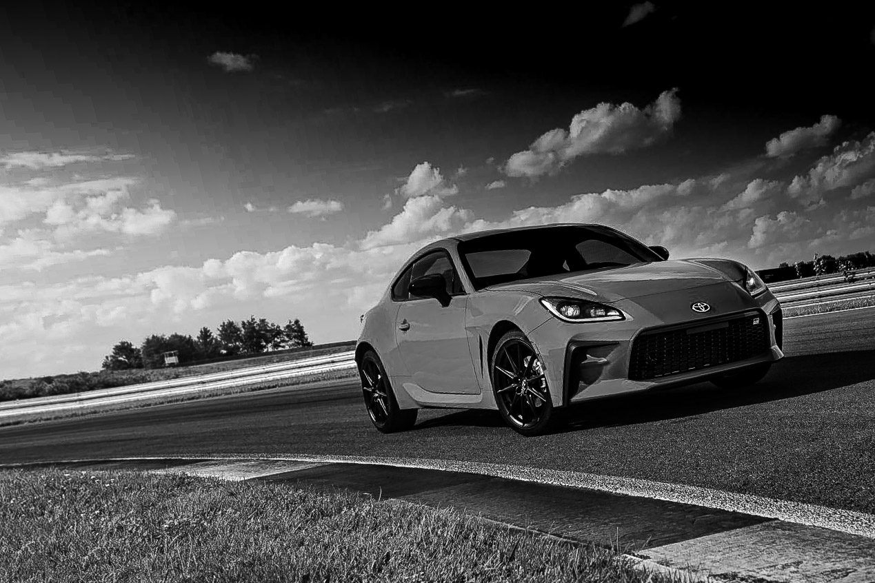 A sleek sports car parked on a race track under a cloudy sky.