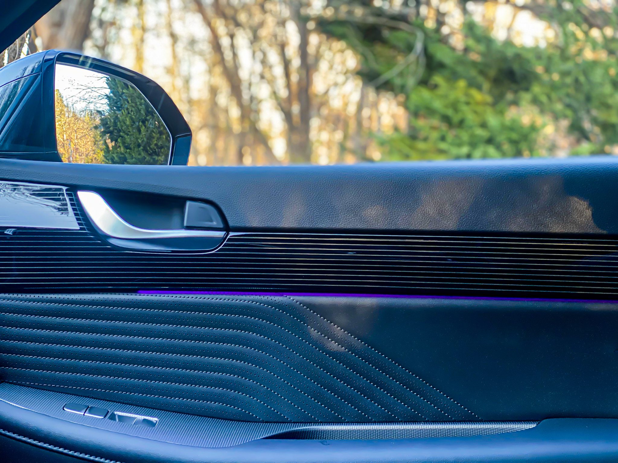 Close-up of a car door interior with ambient purple lighting.