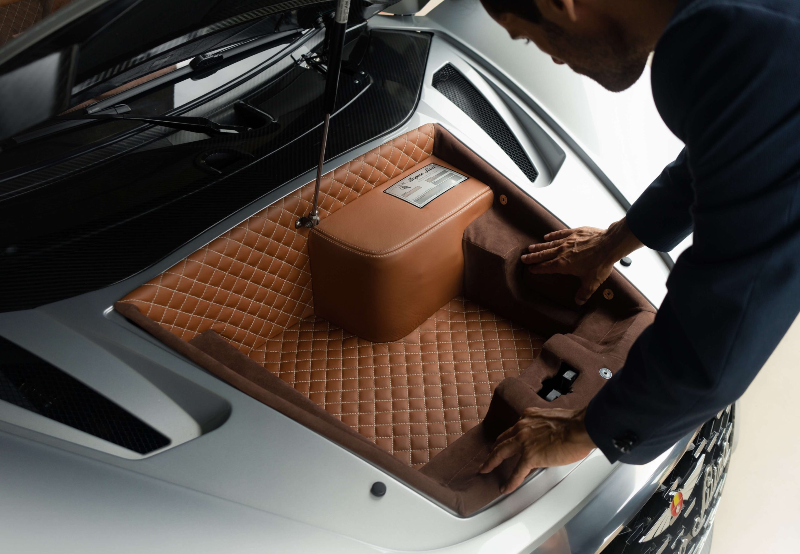Person writing on a clipboard inside a car's trunk.