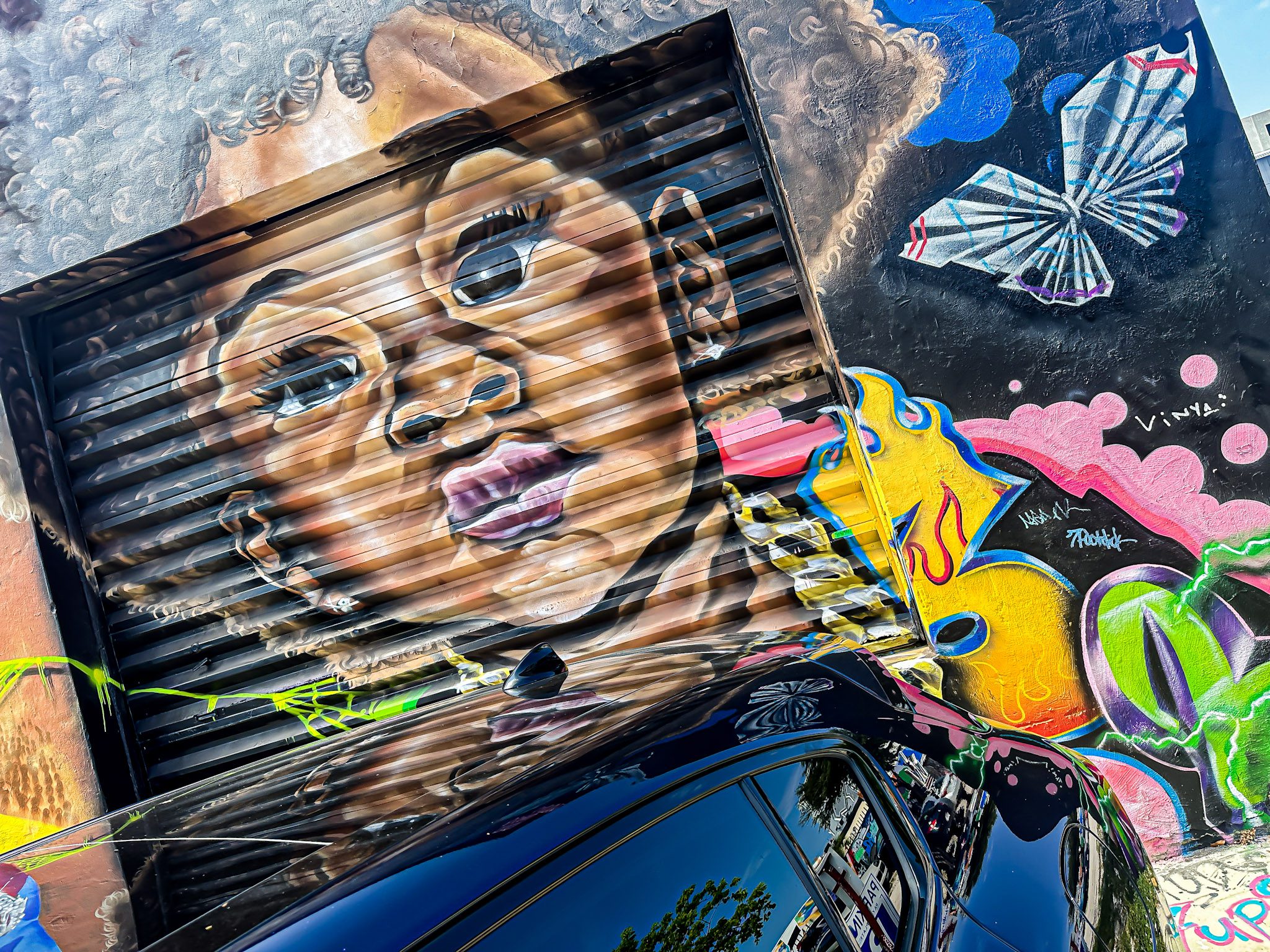 Colorful mural of a young girl wearing glasses painted on a corrugated metal surface.