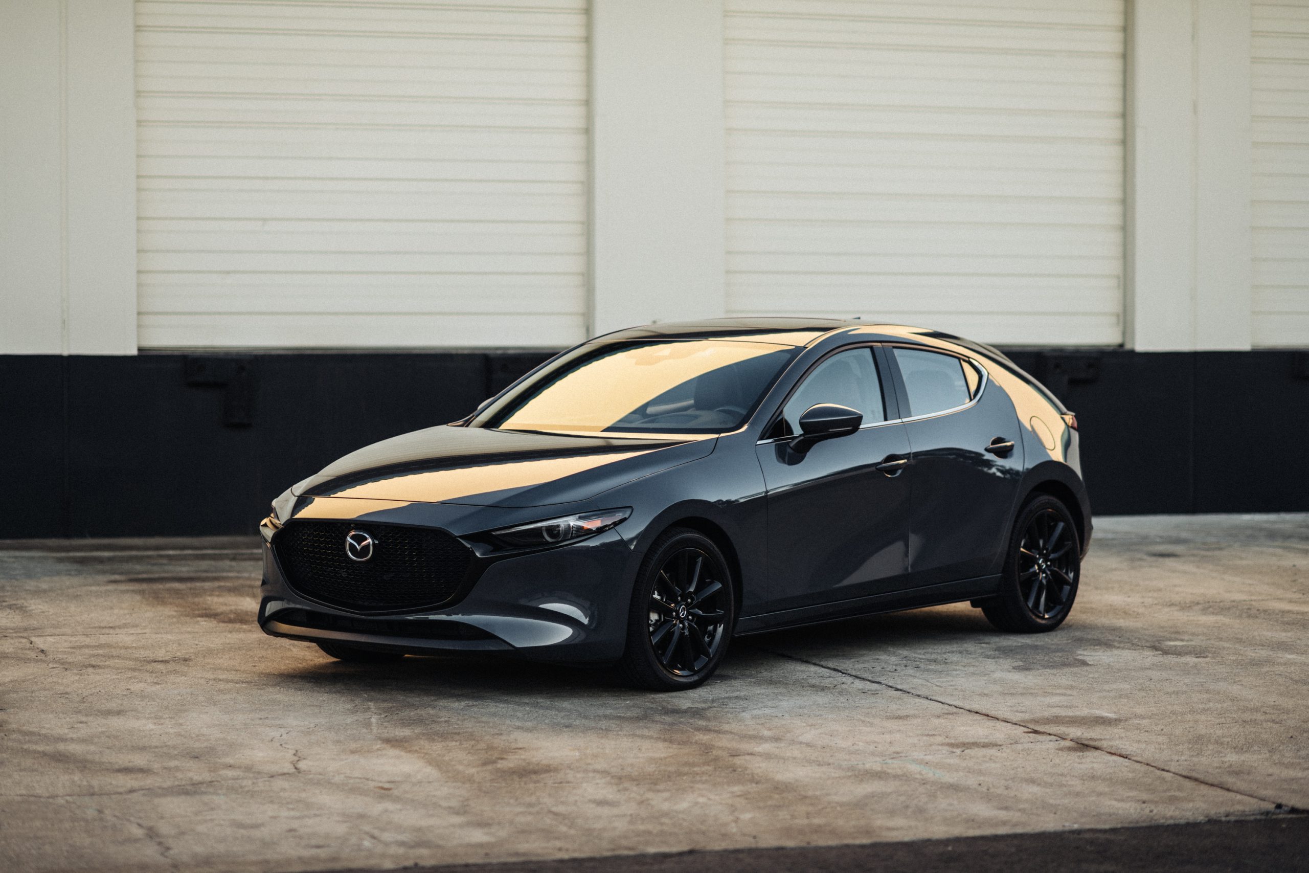 Sleek black Mazda sedan parked against a minimalistic industrial backdrop.