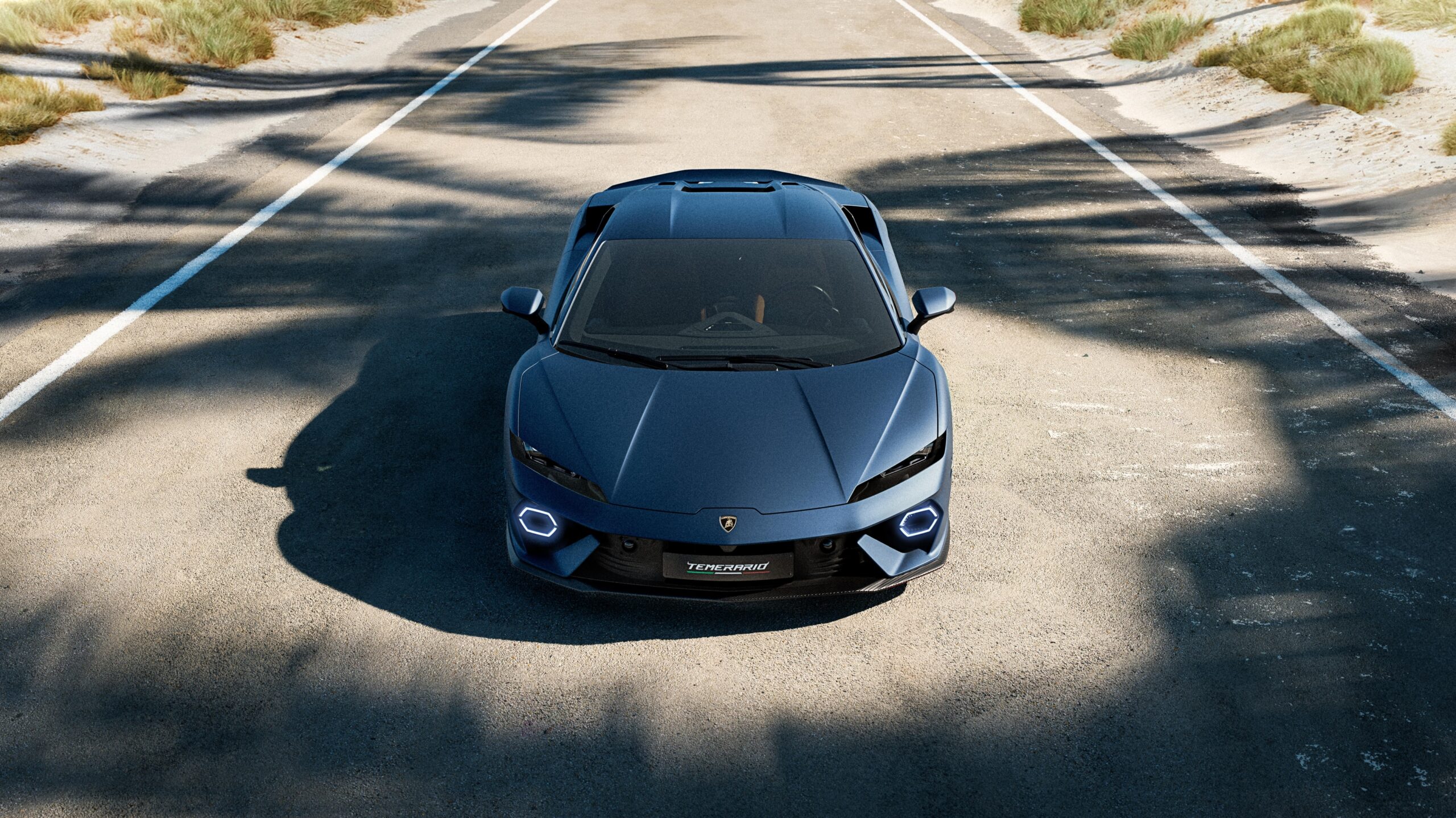 Top view of a sleek black Lamborghini on a sunny road.