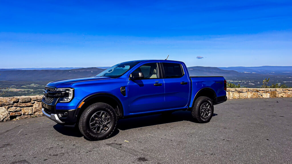 A dynamic image showcasing the **2024 Ford Ranger XLT SuperCrew 4x4** in **Velocity Blue Metallic**, featuring its rugged design, **off-road capability**, and **EcoBoost engine**. The truck is equipped with the **FX4 package**, offering **superior performance** on various terrains. Highlighted elements include **SYNC4 technology**, **towing capacity**, and the vehicle's **mid-size truck versatility**. Perfect for those seeking adventure, durability, and advanced **tech features** in a pickup.