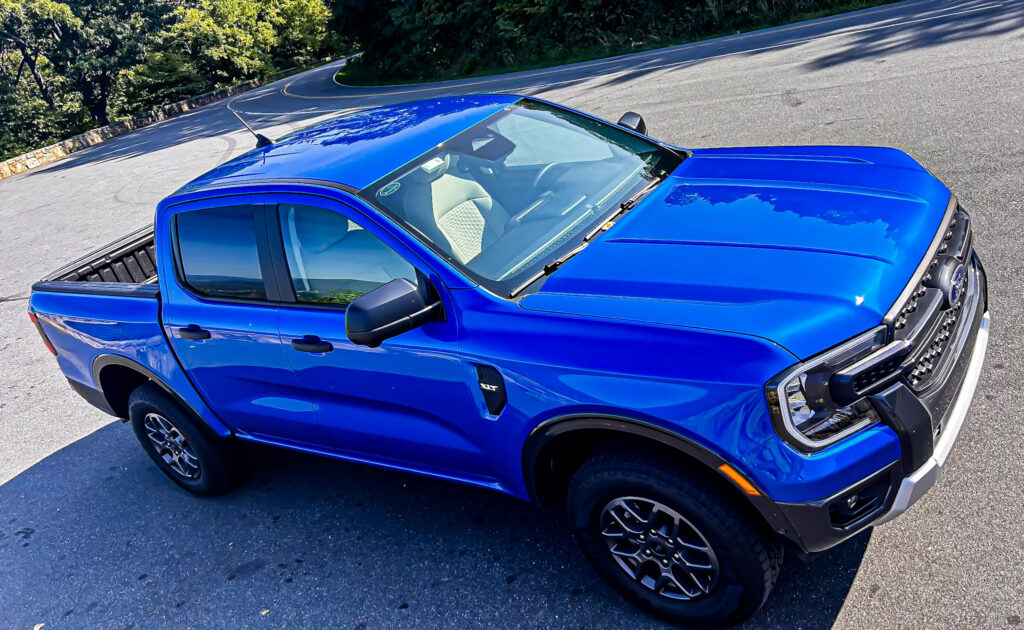 A dynamic image showcasing the **2024 Ford Ranger XLT SuperCrew 4x4** in **Velocity Blue Metallic**, featuring its rugged design, **off-road capability**, and **EcoBoost engine**. The truck is equipped with the **FX4 package**, offering **superior performance** on various terrains. Highlighted elements include **SYNC4 technology**, **towing capacity**, and the vehicle's **mid-size truck versatility**. Perfect for those seeking adventure, durability, and advanced **tech features** in a pickup.