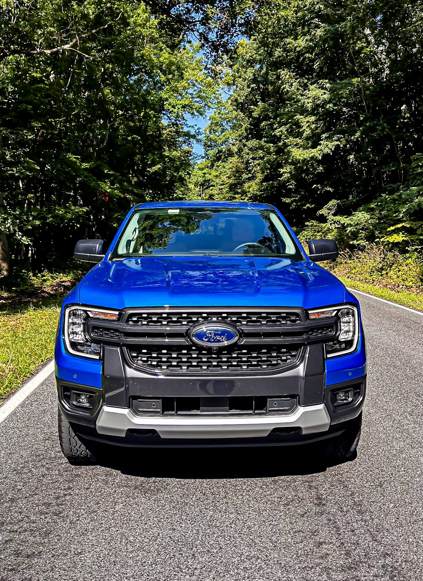 Front view of a blue Ford Ranger on a forest road.