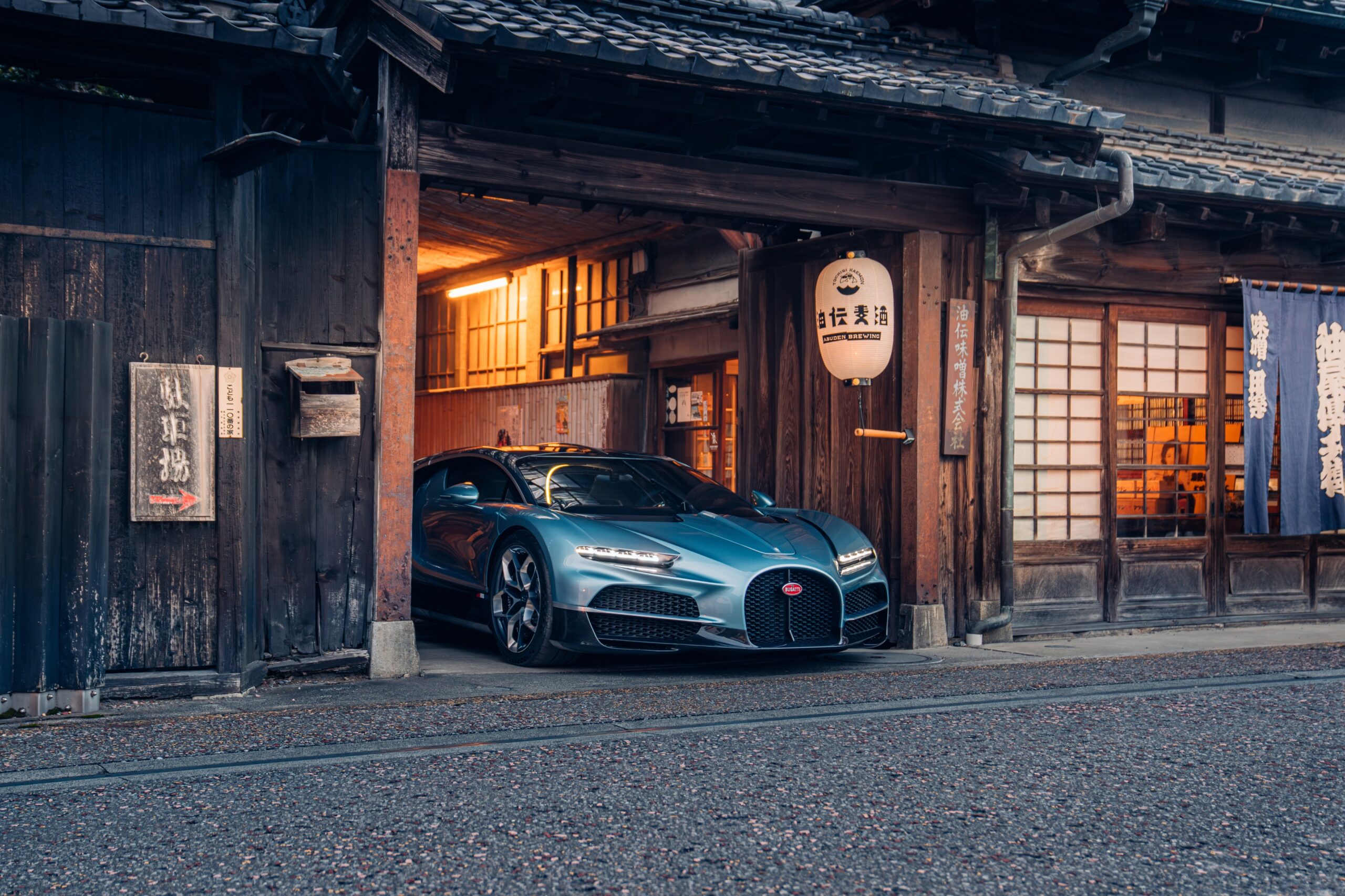 Luxury car parked inside a traditional Japanese building at dusk.