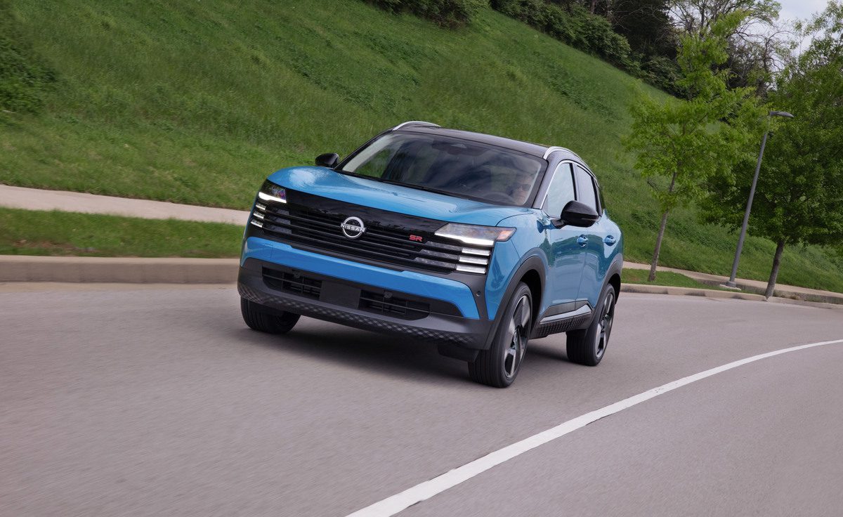 Blue compact SUV driving on a curved road with greenery in the background.