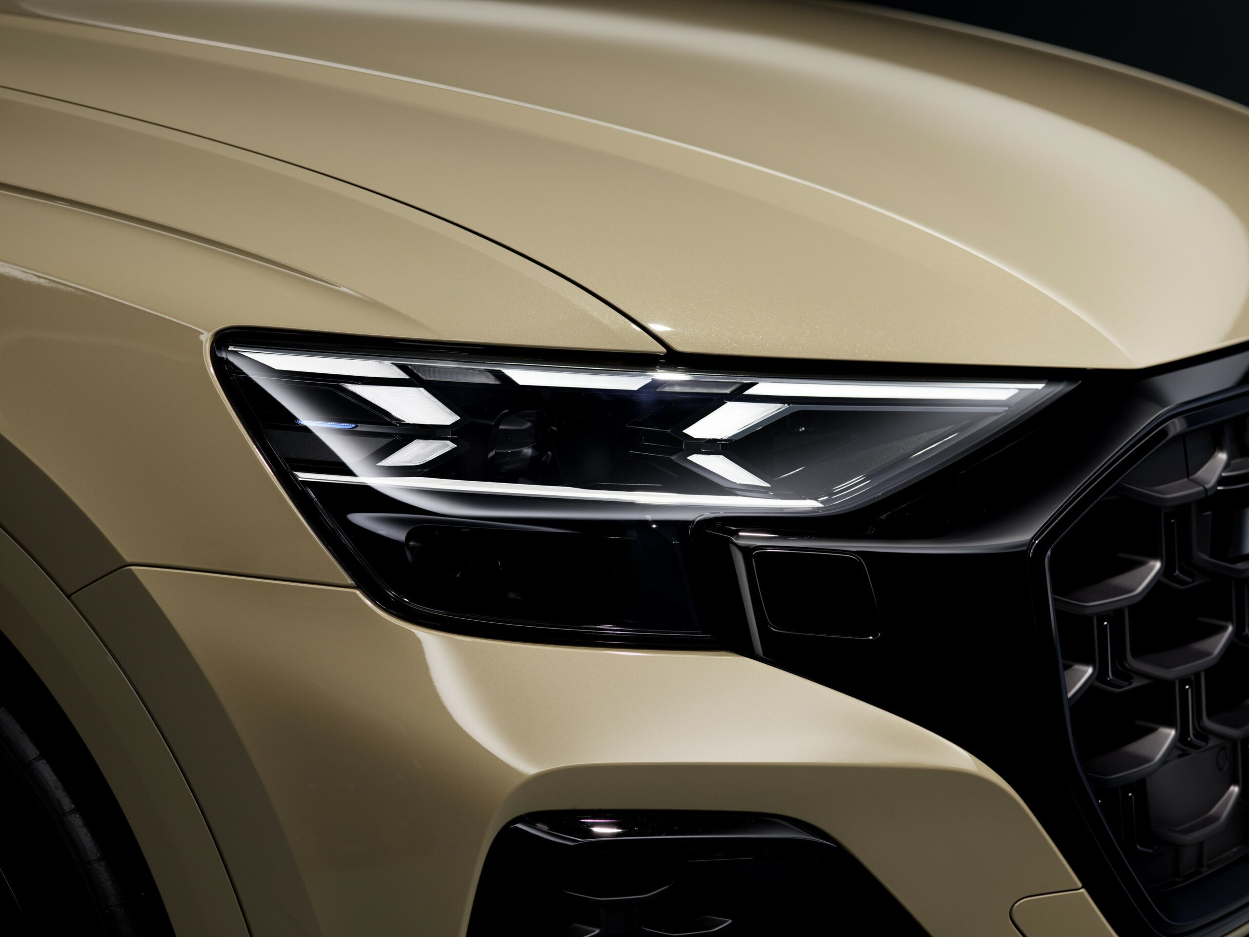 Close-up of a modern car's sleek LED headlight on a beige body.