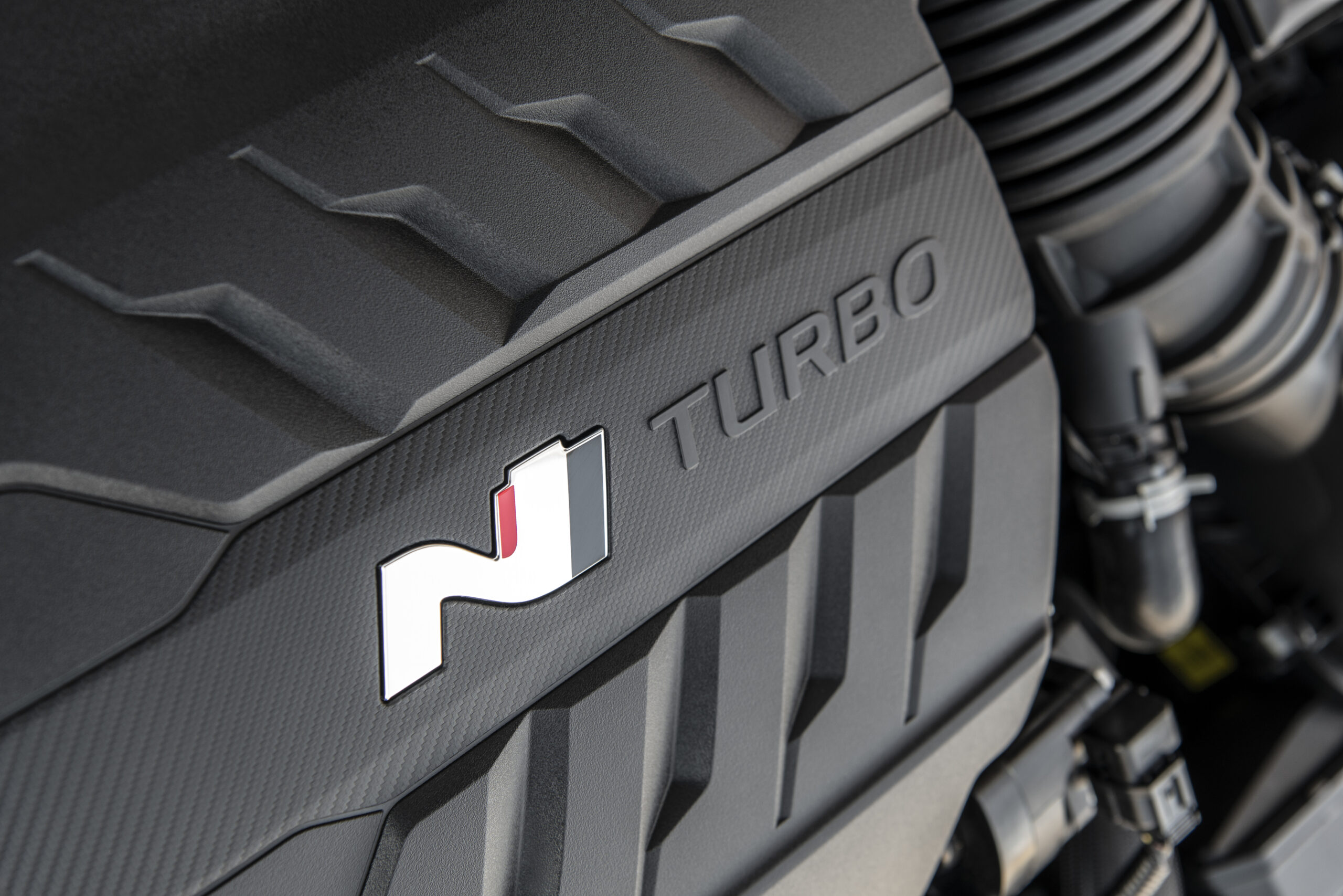 Close-up of a turbocharged engine cover with an 'N' logo.