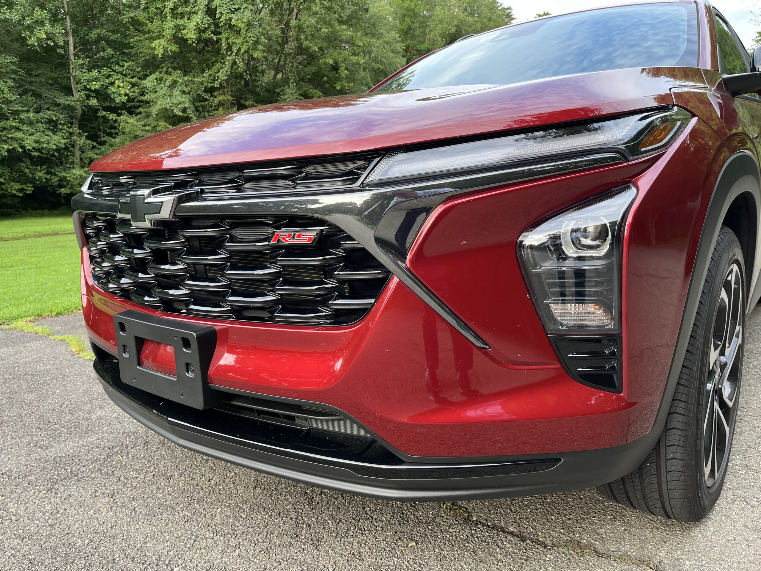 Close-up of a red car's front grille and headlight design.