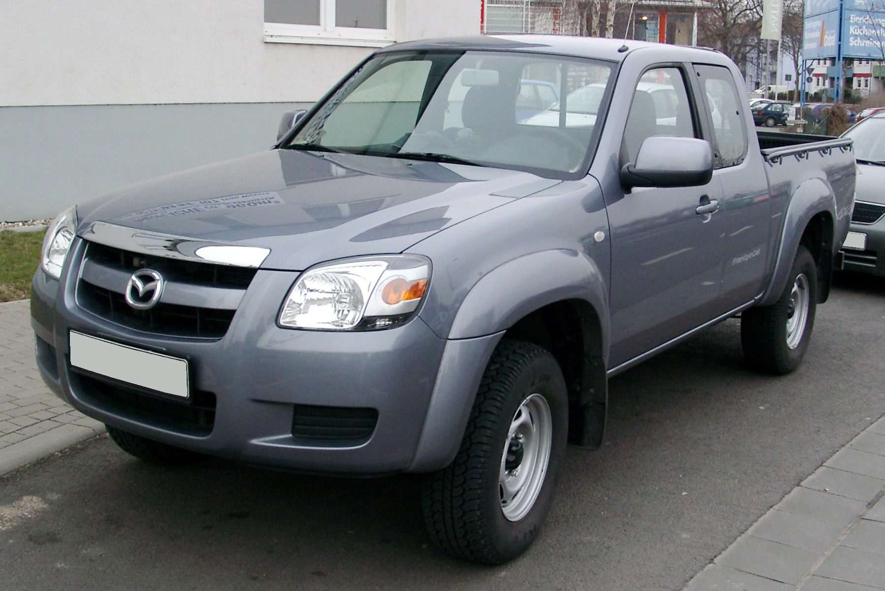 A gray pickup truck parked on the street near a building.