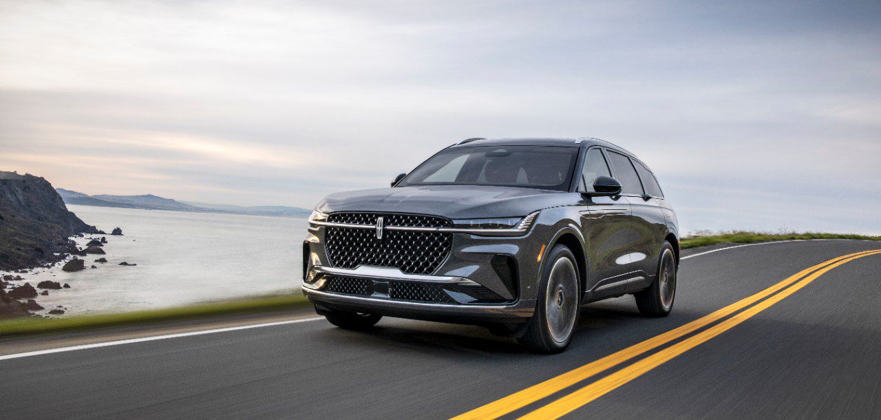 A sleek black luxury SUV driving on a coastal road.