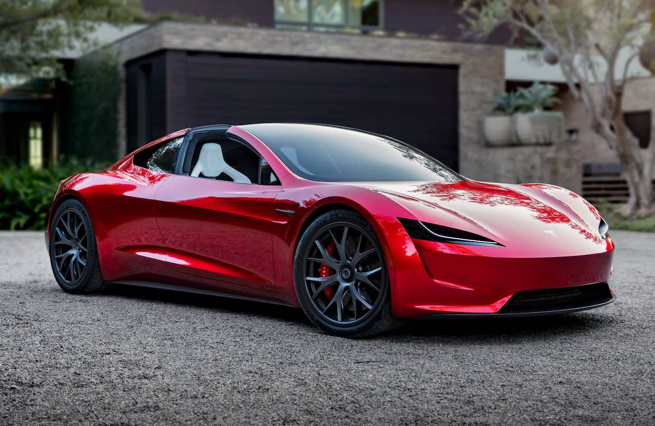 Sleek red sports car parked on a driveway with modern house background.
