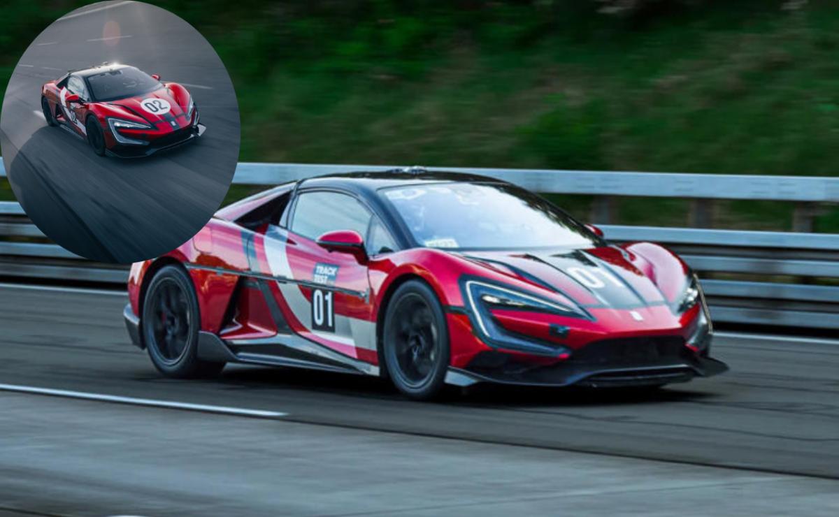 Red race car speeding on a track with a trailer attached.