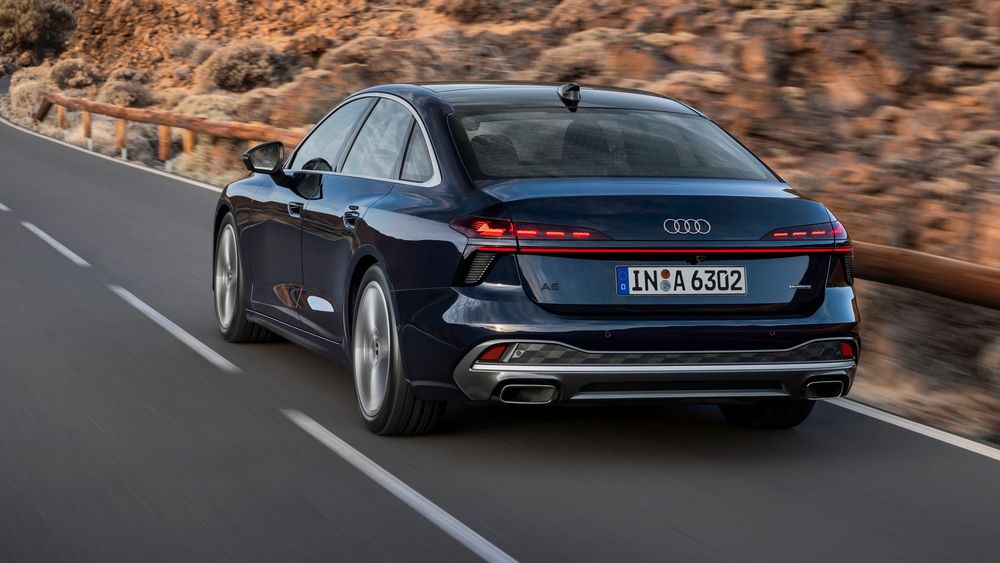 Rear view of a sleek black Audi sedan driving on a road.