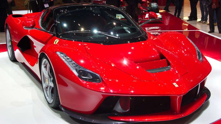 Sleek red sports car with glossy finish at an auto show.