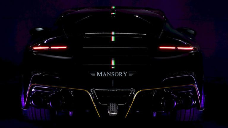 Rear view of a sleek black Mansory luxury car with illuminated tail lights.