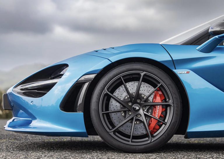 Close-up of a sporty blue car's front wheel with red brake calipers.