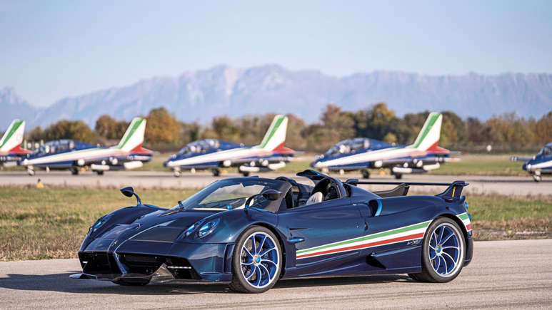 Luxury sports car with Italian flag stripes parked near planes and mountains.