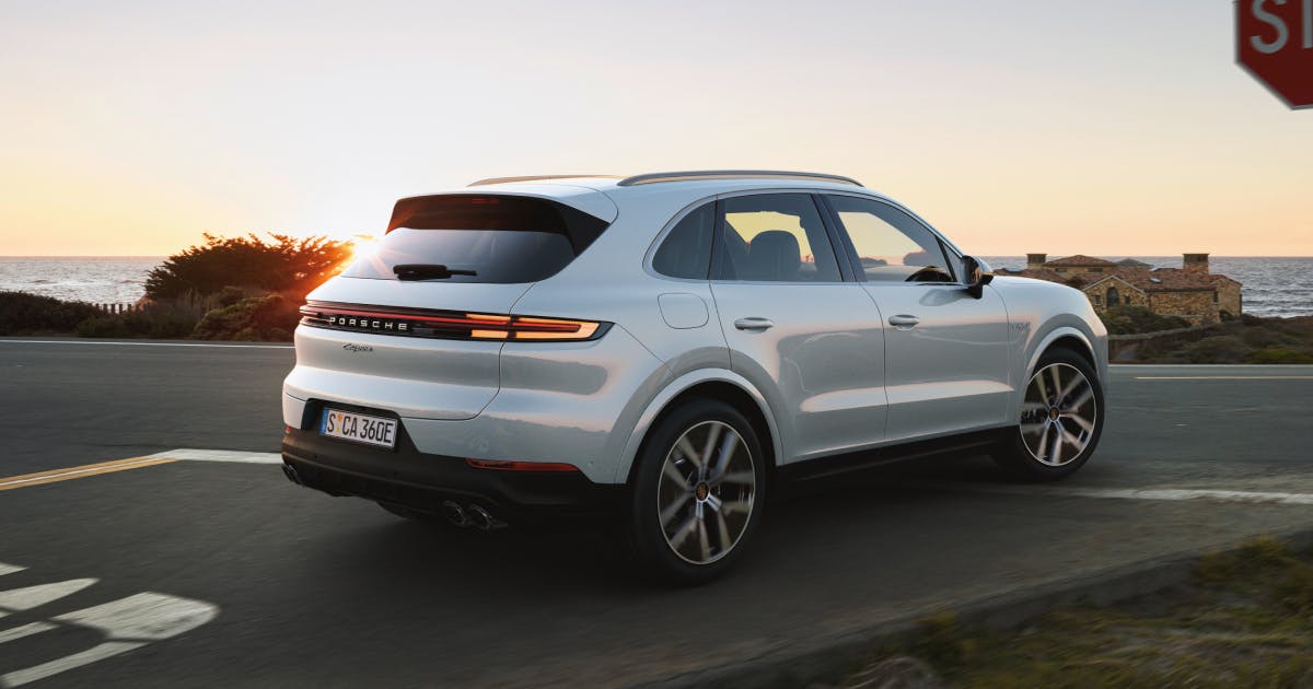 White luxury SUV driving on a road during sunset.