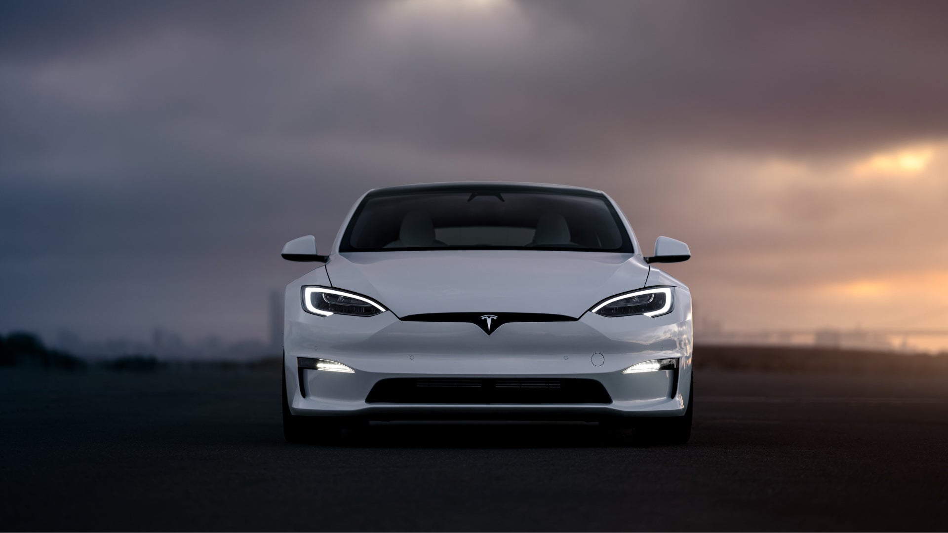 Front view of a sleek white Tesla car at dusk.