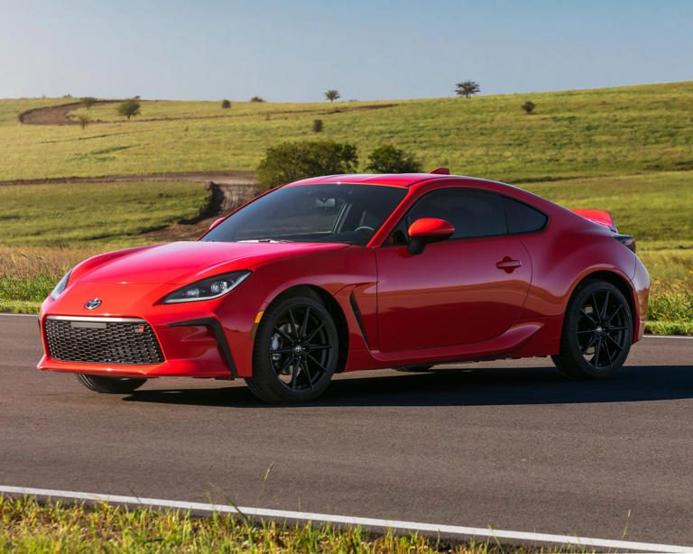 Red sports car on a racetrack under clear skies.