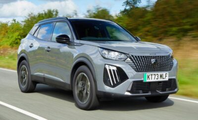 Silver Peugeot SUV driving on a highway with trees in the background.