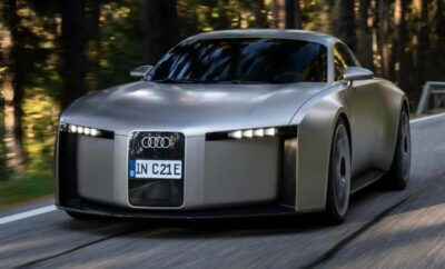 A sleek silver Audi concept car driving on a forest road.