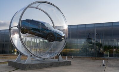 A car displayed inside a large transparent circular structure outdoors.