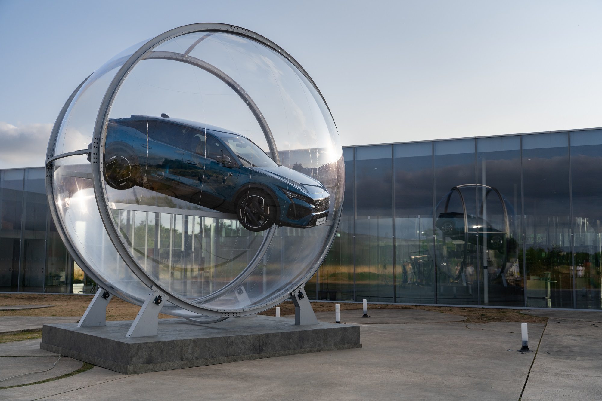 A car displayed inside a large transparent circular structure outdoors.