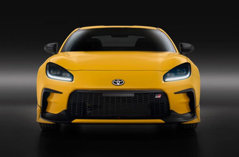 Front view of a sleek yellow sports car with aggressive headlights and grille.