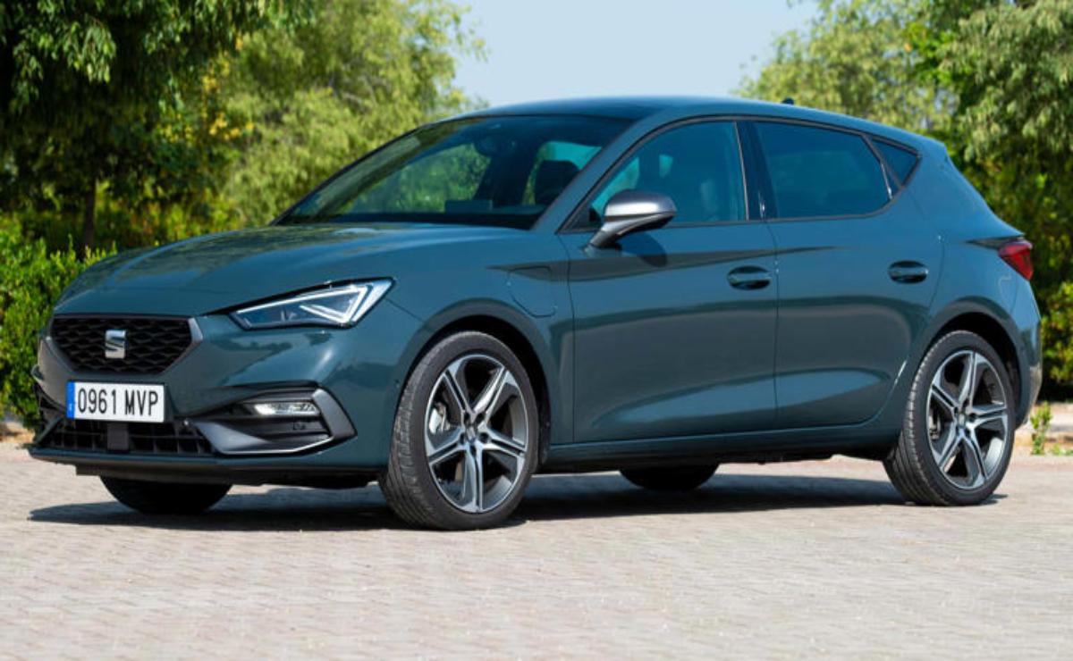 A sleek dark gray sedan parked on a sunny road surrounded by greenery.