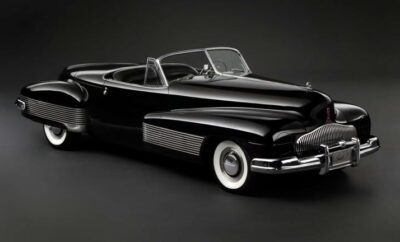 Classic black convertible car with whitewall tires in a studio setting.