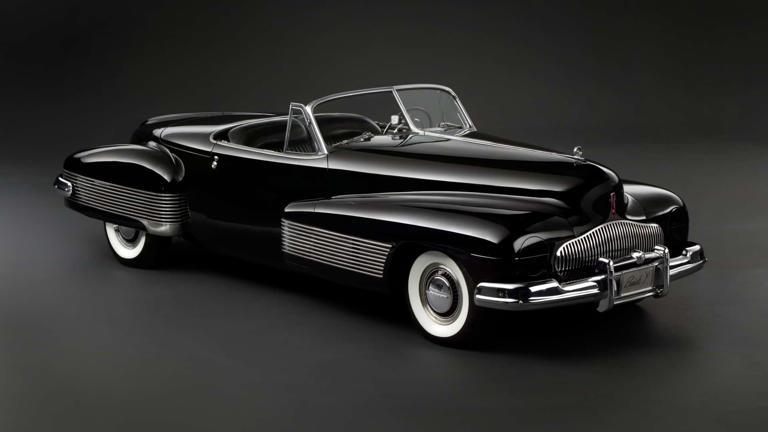 Classic black convertible car with whitewall tires in a studio setting.