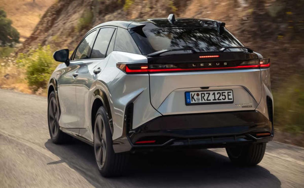 Silver electric SUV driving on a road with trees in the background.