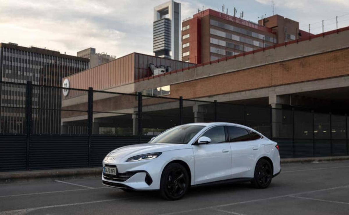 White electric car parked in an urban area with modern buildings.