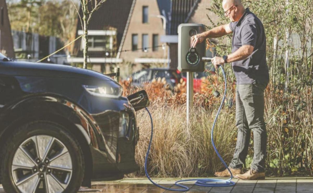 Man charging an electric car at home with a portable charger.