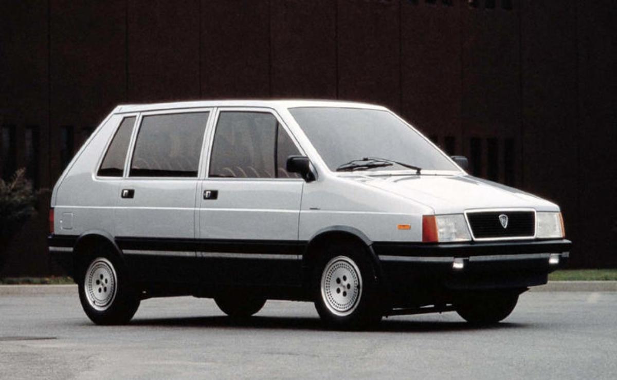 A white compact hatchback car parked against a dark background.
