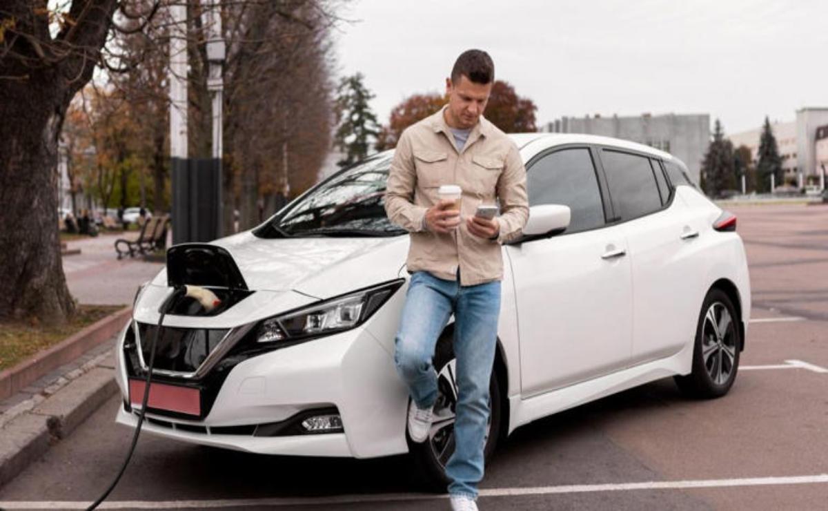 Man standing next to a white car, using his phone.