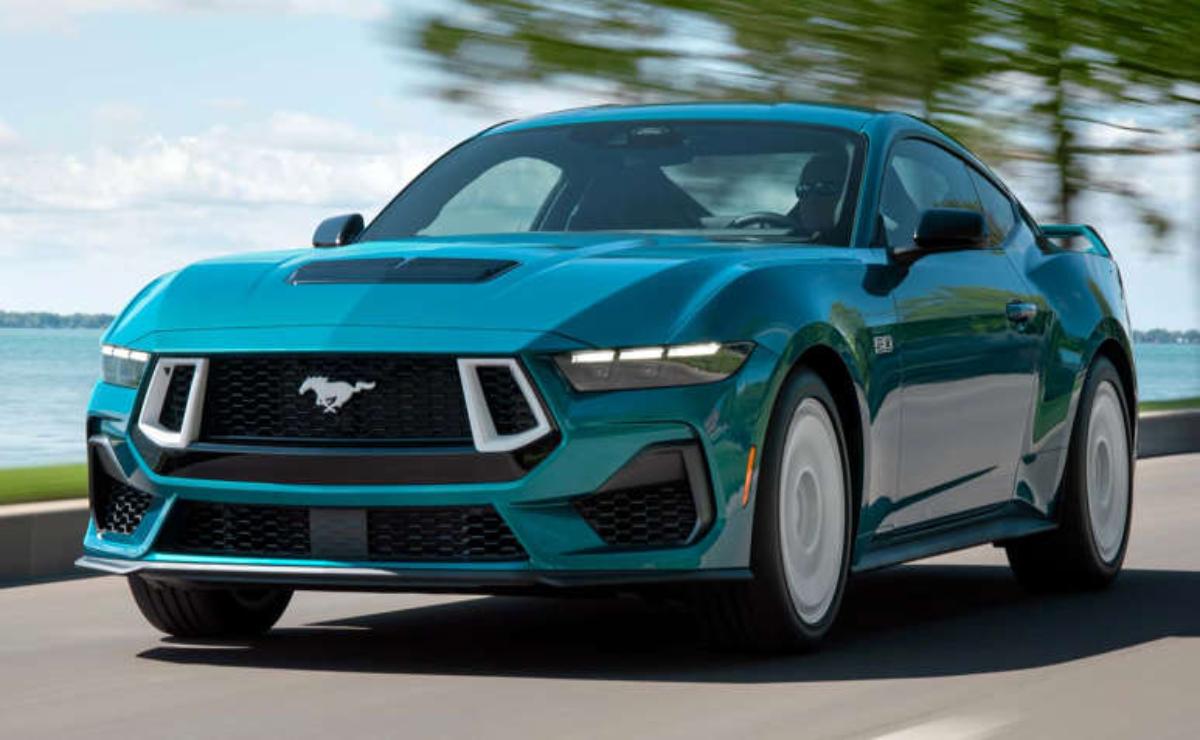 A teal Ford Mustang driving on a road with motion blur.