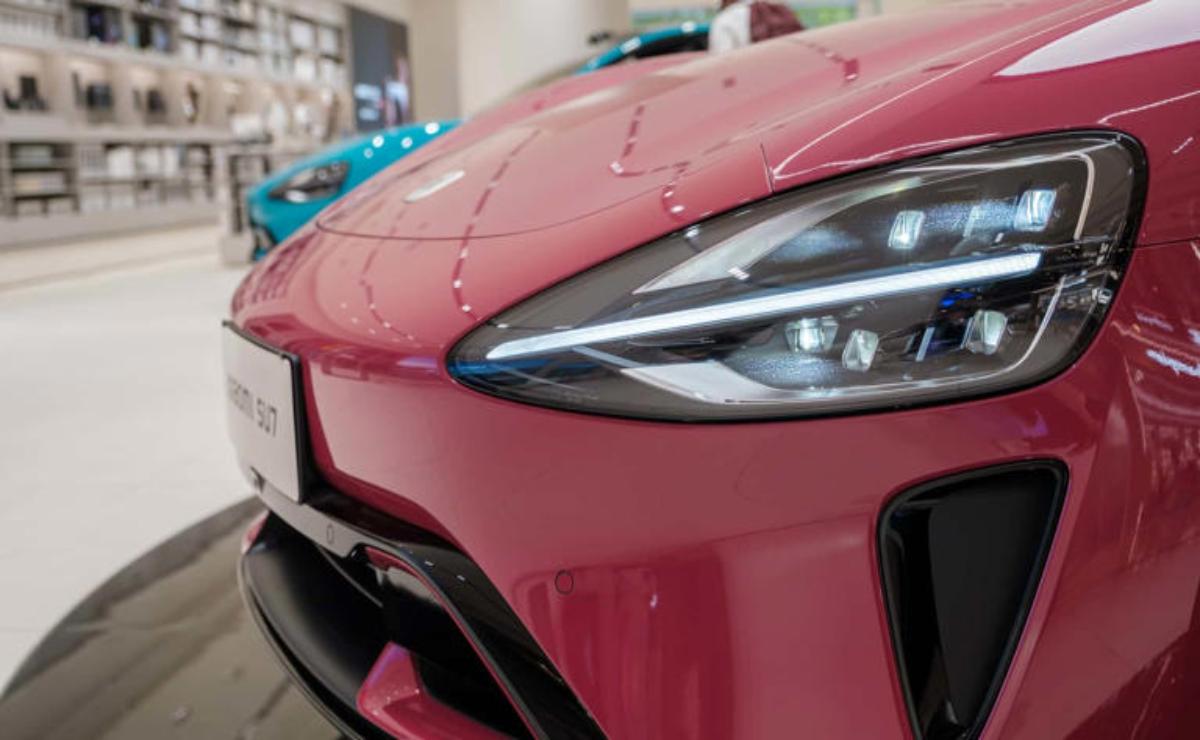 Close-up of a shiny red car's front headlight and grille.