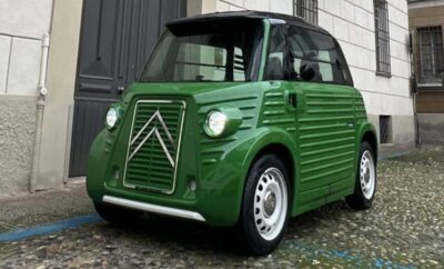 A vintage green Citroën 2CV car parked near a building.