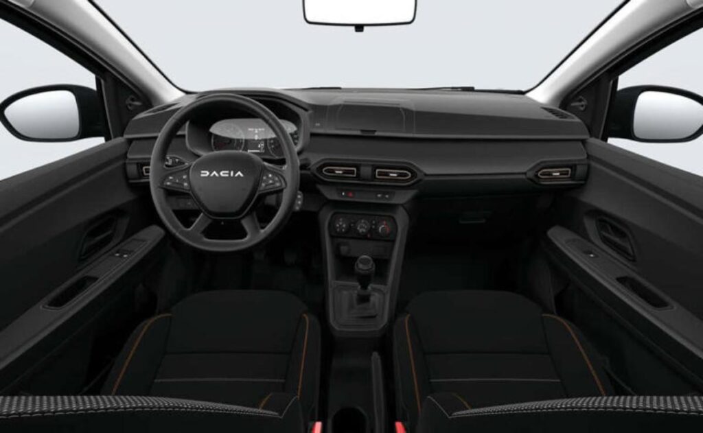 A man working on his laptop and writing in a notebook at a desk.